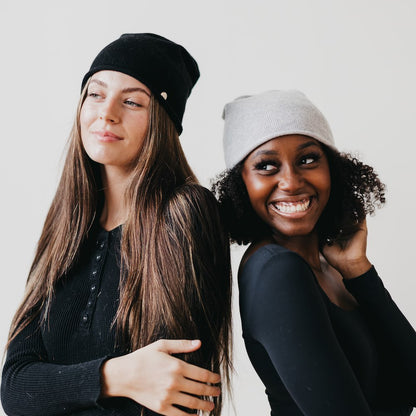 Two women wearing beanies against a plain background