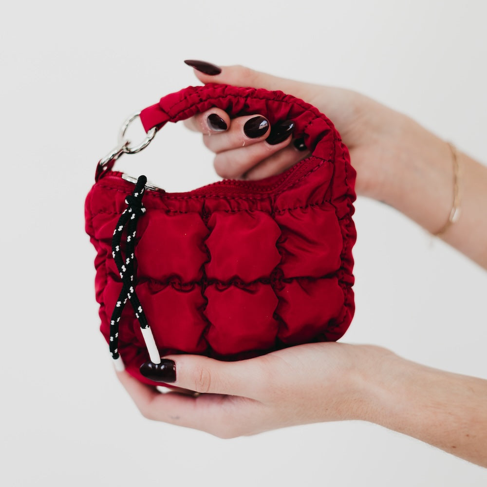Red textured handbag held by a person on a white background