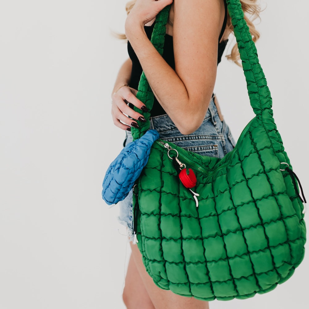 Green textured handbag held by a person against a white background