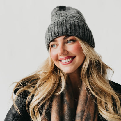 Woman wearing a gray knit beanie with satin lined interior and scarf against a white background