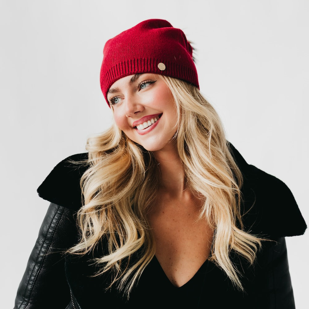 Woman wearing a red beanie and black jacket on a white background
