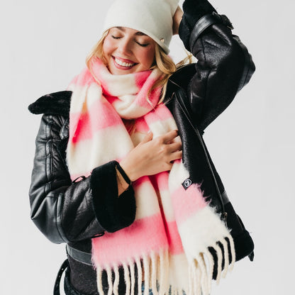 Woman wearing a pink and white scarf with a black leather jacket on a light gray background