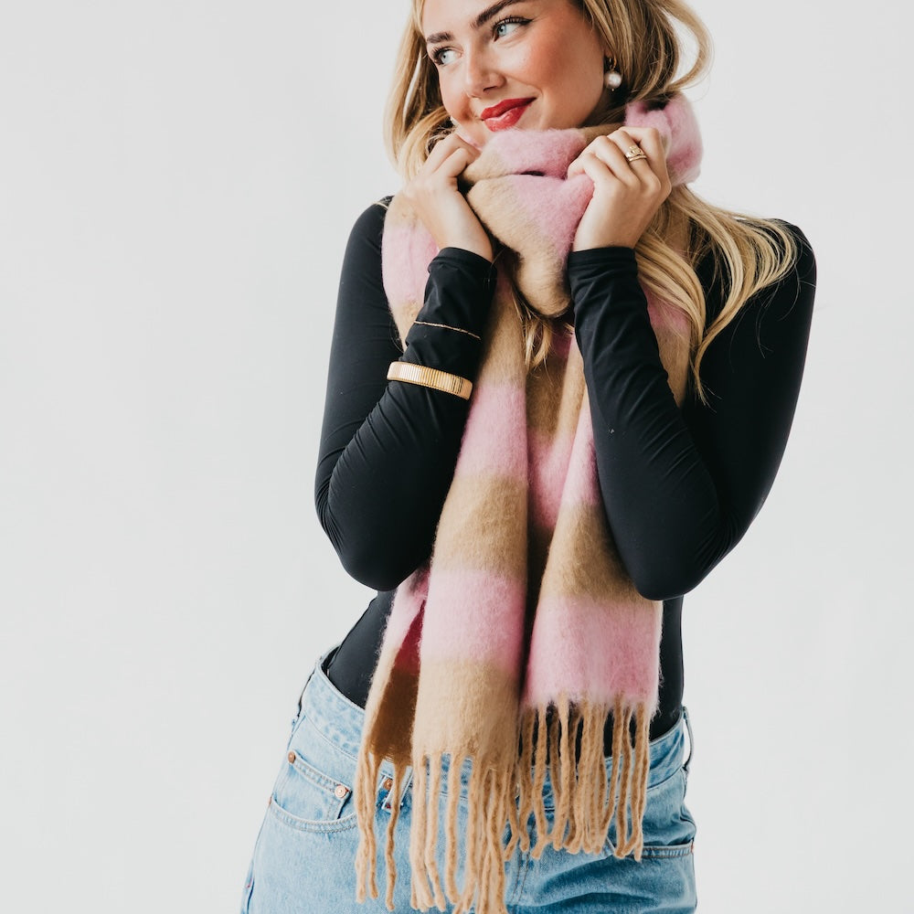 Woman wearing a pink and brown checkered scarf against a white background