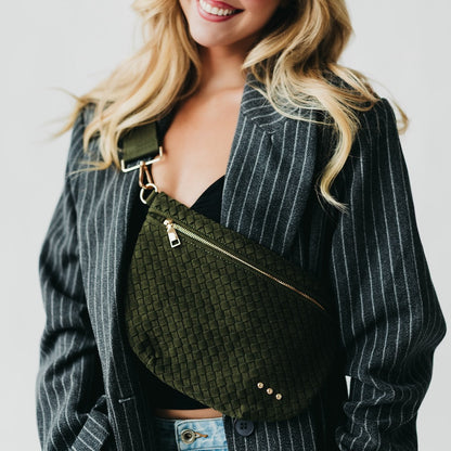 Woman wearing a green woven bag with a plain background