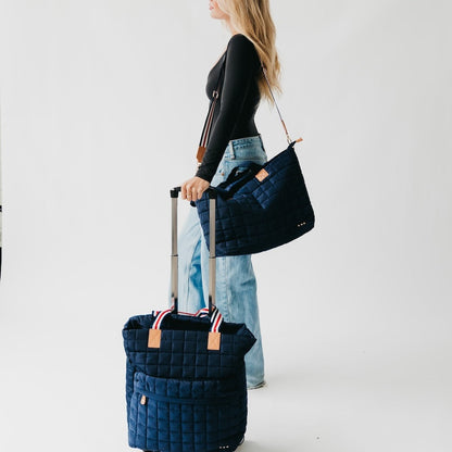 Woman holding a navy quilted bag with a white background