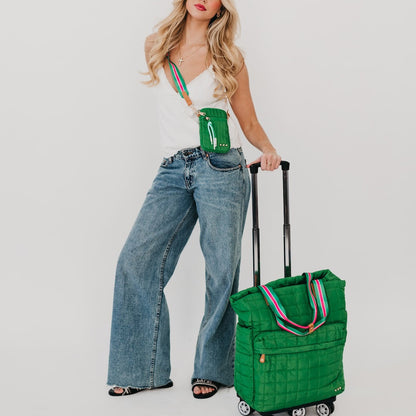 Woman holding a green suitcase with a matching green bag on a plain background