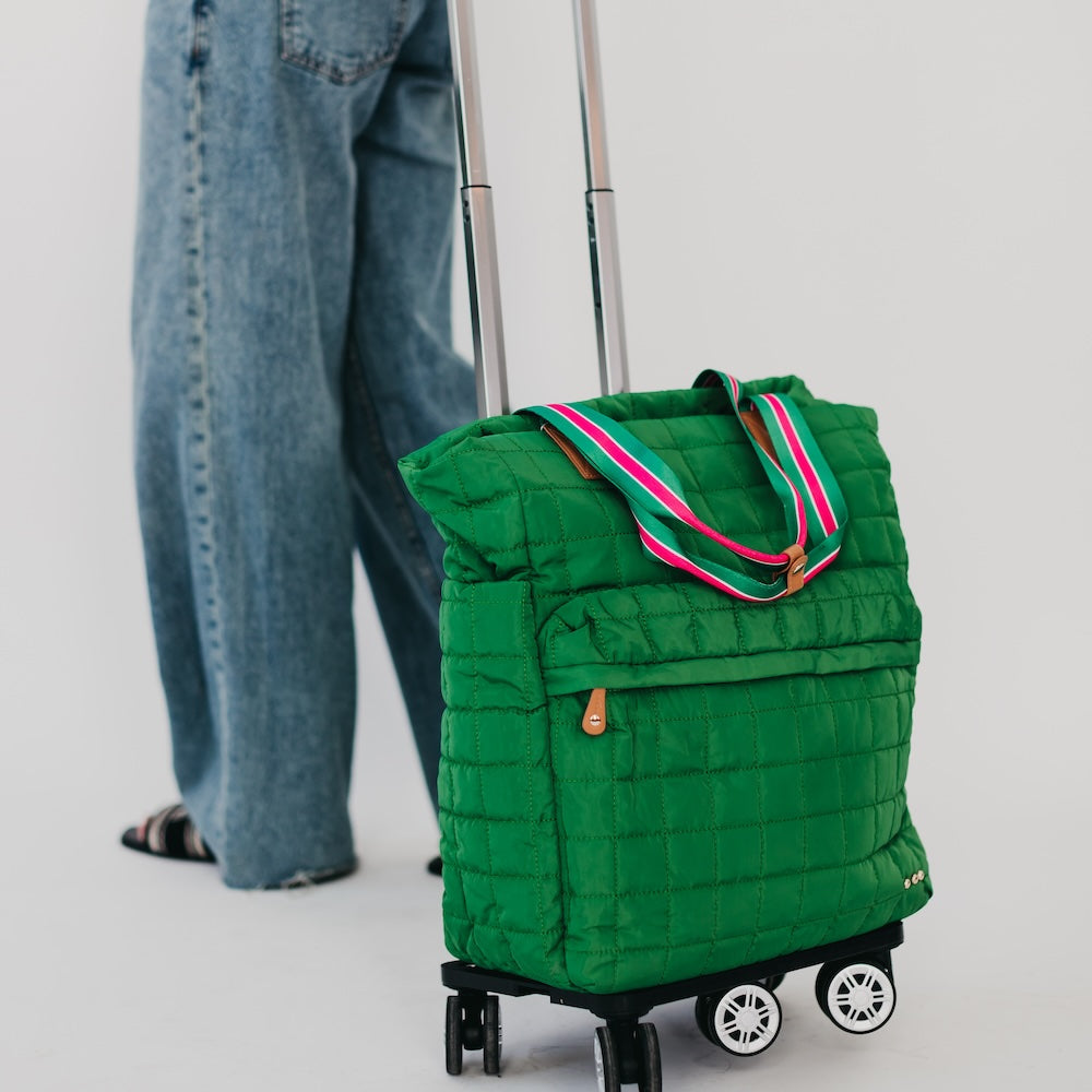 Green quilted rolling bag with pink straps on a light gray background