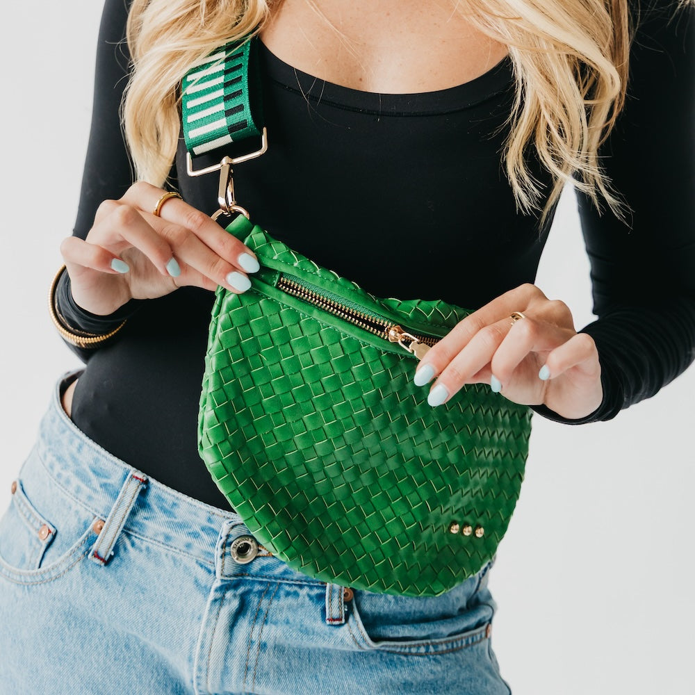 Person holding a green woven bag with a white background