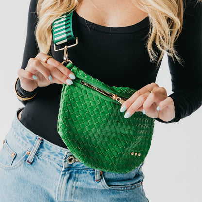 Person holding a green woven bag with a white background