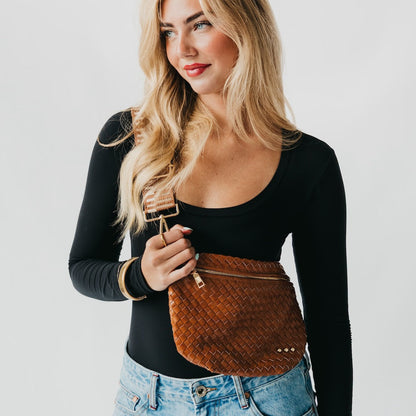 Woman holding a brown woven bag against a plain background