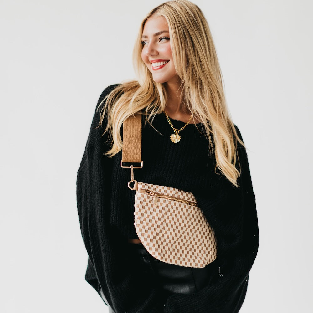 Woman wearing a black sweater with a beige checkered bag on a white background