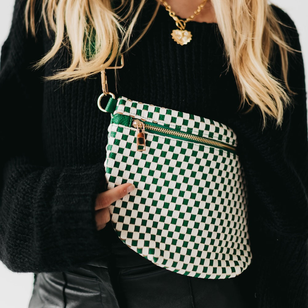 Green and white checkered bag held by a person wearing a black sweater.