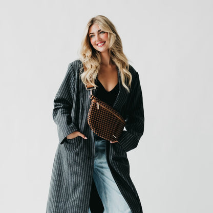 Woman holding a studded handbag against a plain background