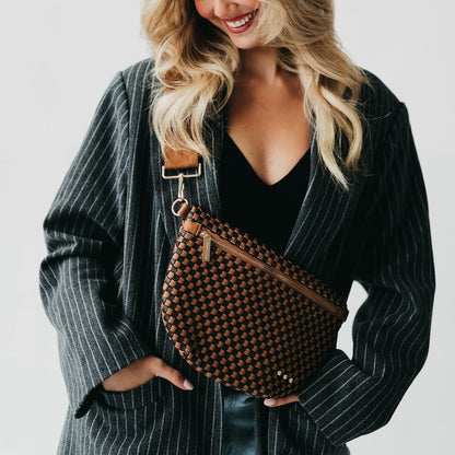 Woman holding a woven brown bag against a plain background