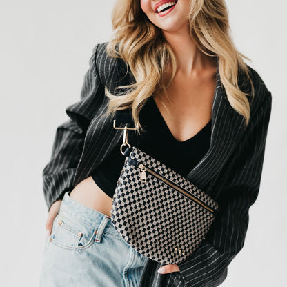 Woman wearing a black and white checkered bag with a plain background