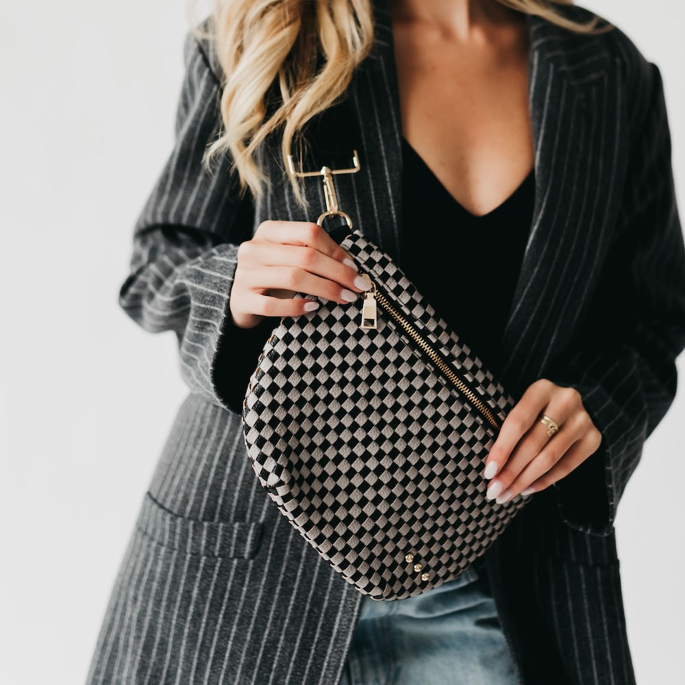 Person holding a black and gray checkered pouch with a plain background