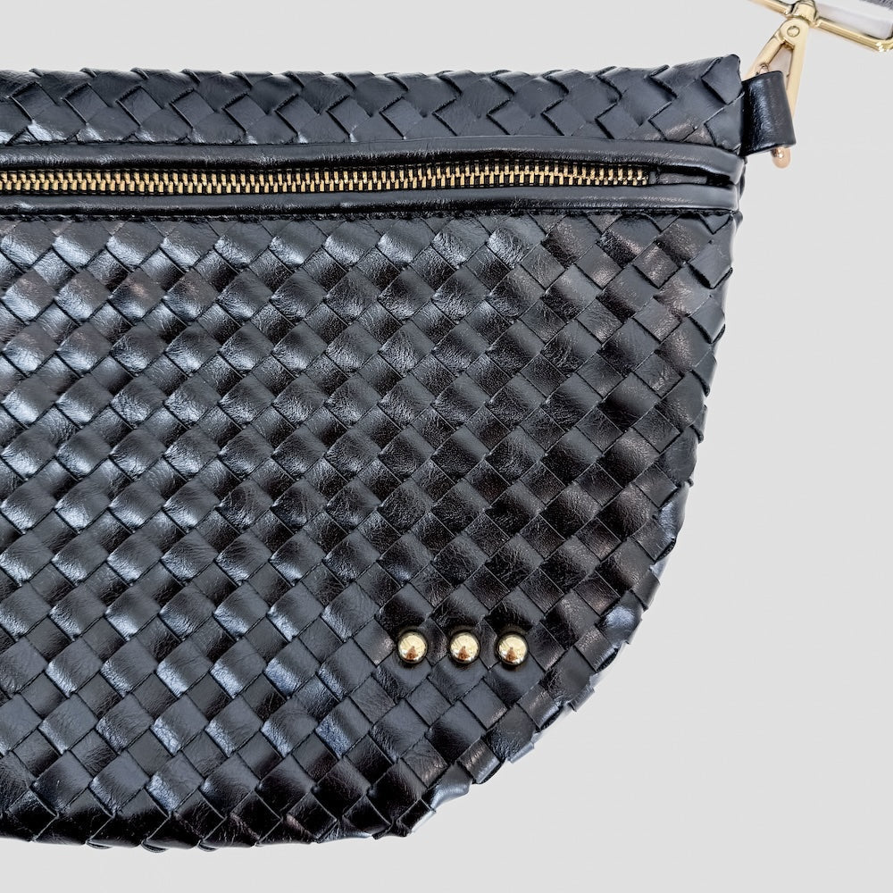 Black woven handbag with gold zipper and studs on a light gray background