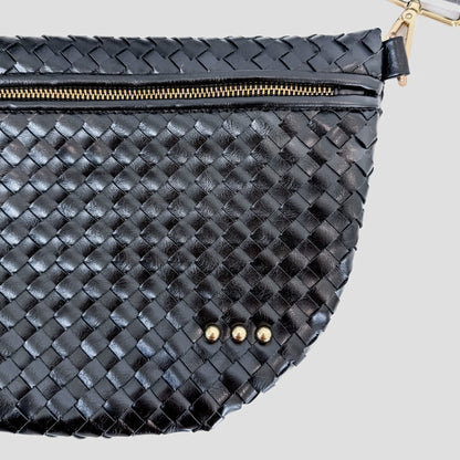 Black woven handbag with gold zipper and studs on a light gray background