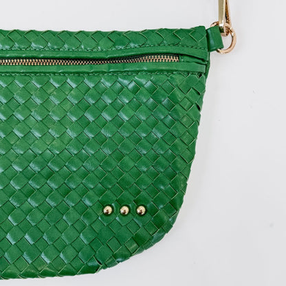 Green woven handbag with gold zipper and studs on a white background